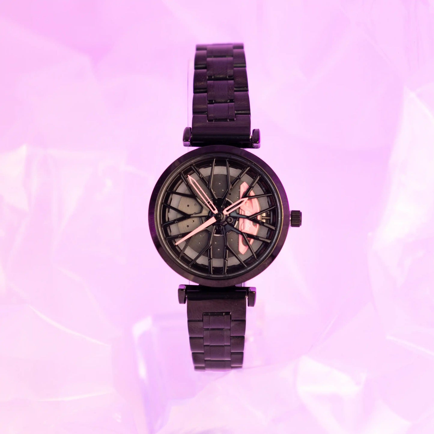 This image showcases the DriftElement Lady Like Edition watch. A women's timepiece featuring a motorsport-inspired rim design. The watch has a black metallic bracelet and casing, with striking pink accents on the watch hands and markers, highlighting its innovative design. The dial mimics the intricate pattern of a car's rim, blending automotive passion with timekeeping elegance. Created by a young startup from Germany, DriftElement is known for its fusion of horological craftsmanship and automotive design.