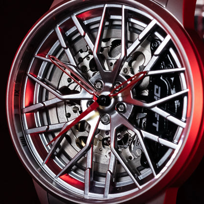 An automatic Motorsport EMS Edition wheel watch with a detailed rim design by DriftElement, a young startup from Germany. The watch features an innovative design with a visible mechanical movement through the spokes of a rim-styled face, accented with red details and metallic silver finishes, embodying a fusion of horology and automobile aesthetics.